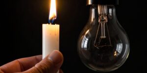 una vela encendida junto a una bombilla apagada