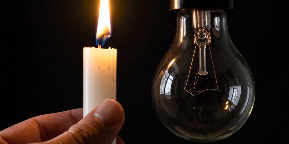 una vela encendida junto a una bombilla apagada